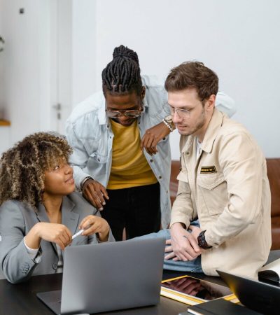 man and two women having a discussion while looking at the laptop